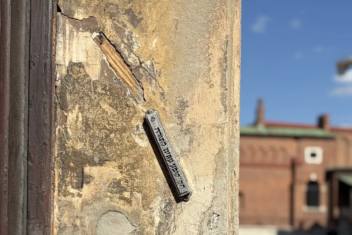 A mezuzah on the corner of a townhouse on Józefa St. in Kazimierz, with the district's historic buildings behind