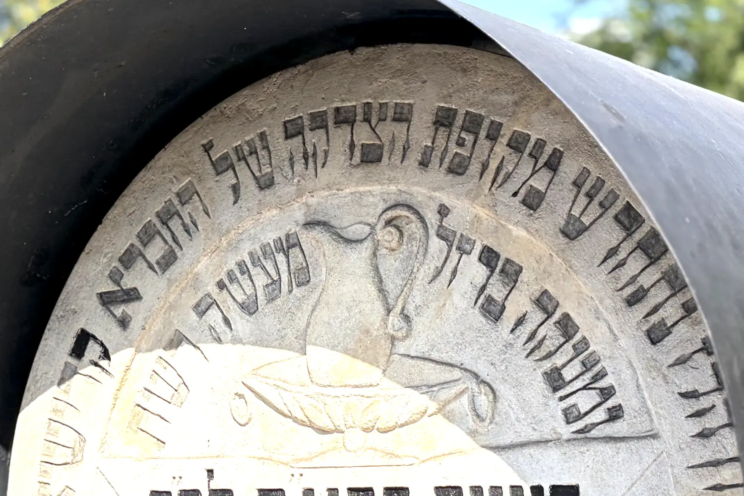 A matzevah with an ornate Hebrew inscription and a vessel motif at the Remah Cemetery in Kazimierz