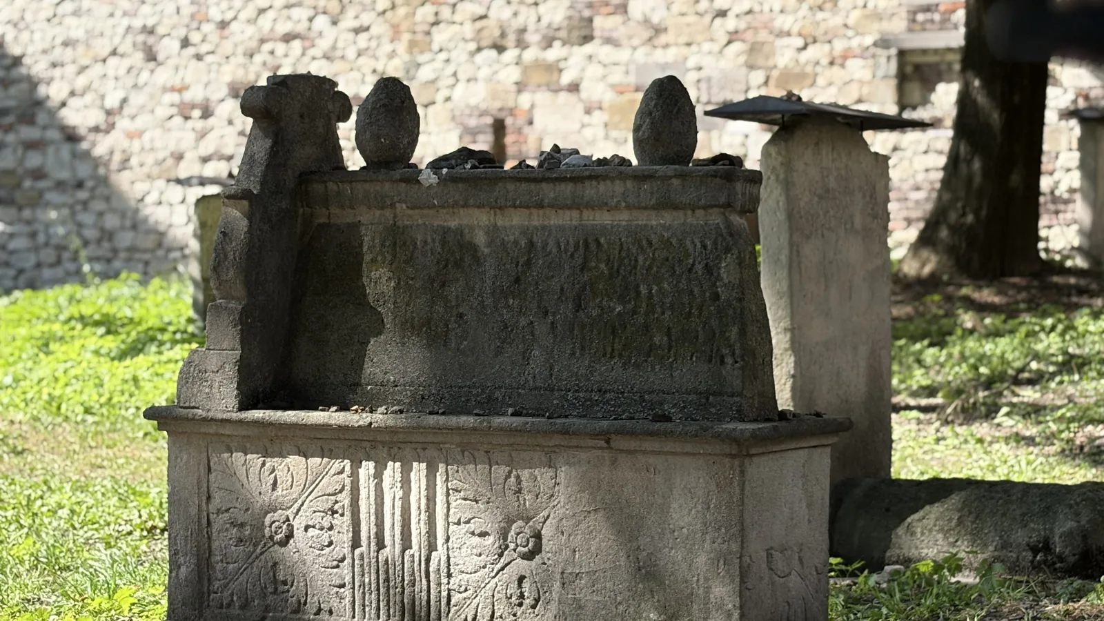Carved stone chest-tomb with rosettes in an old Jewish cemetery, with memorial pebbles placed on its lid