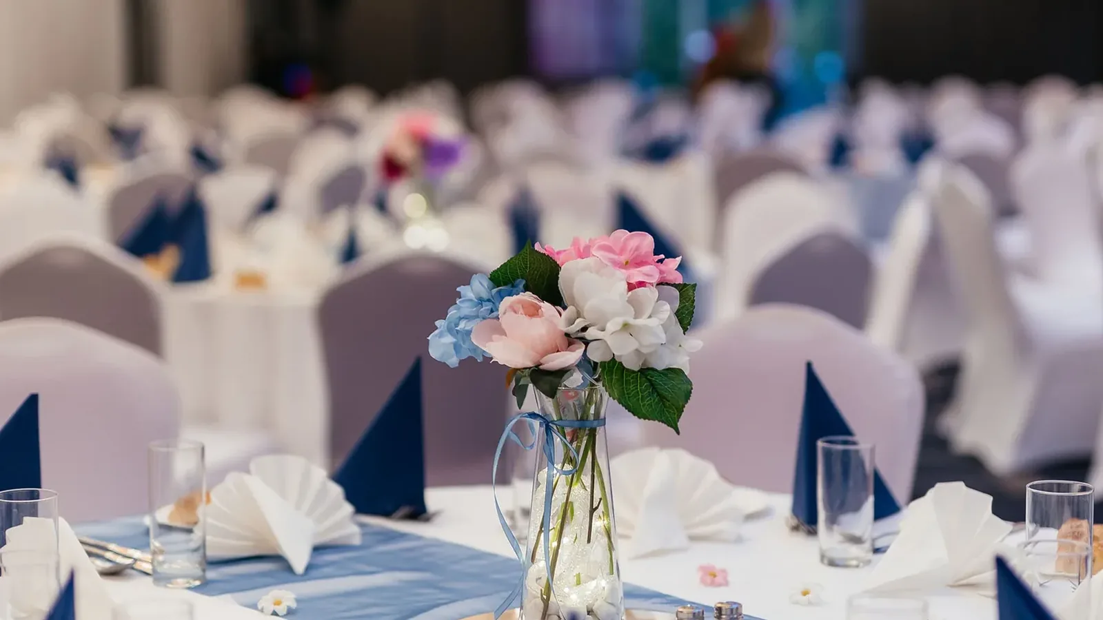 An elegantly set hall table for a group Shabbat dinner - flowers, challah and napkins